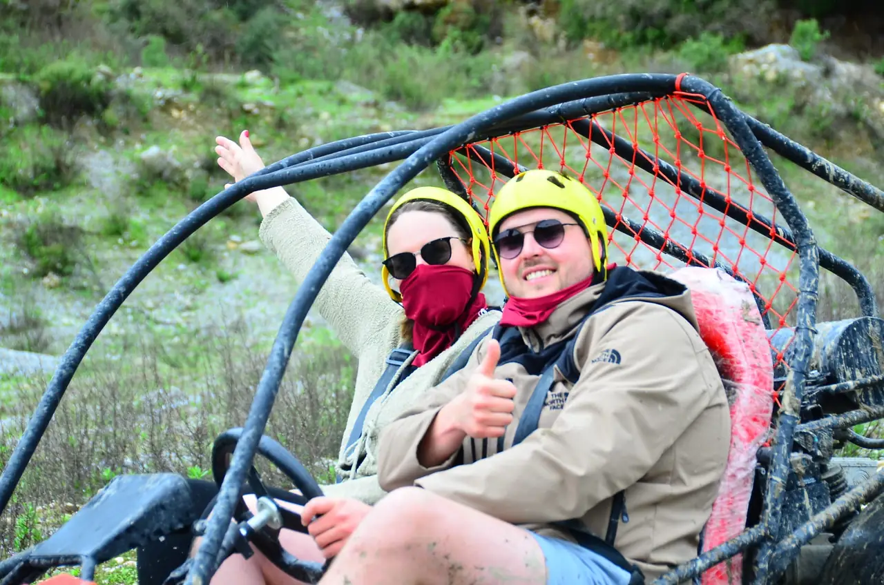 Guests in helmets and dust masks riding a two-seater buggy near Belek