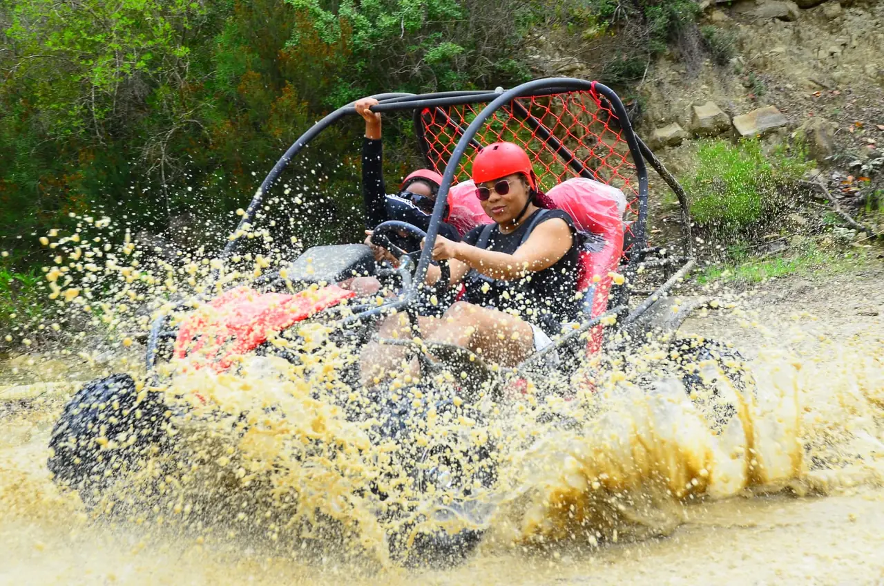 Buggy splashing through a shallow river surrounded by pine forest near Belek