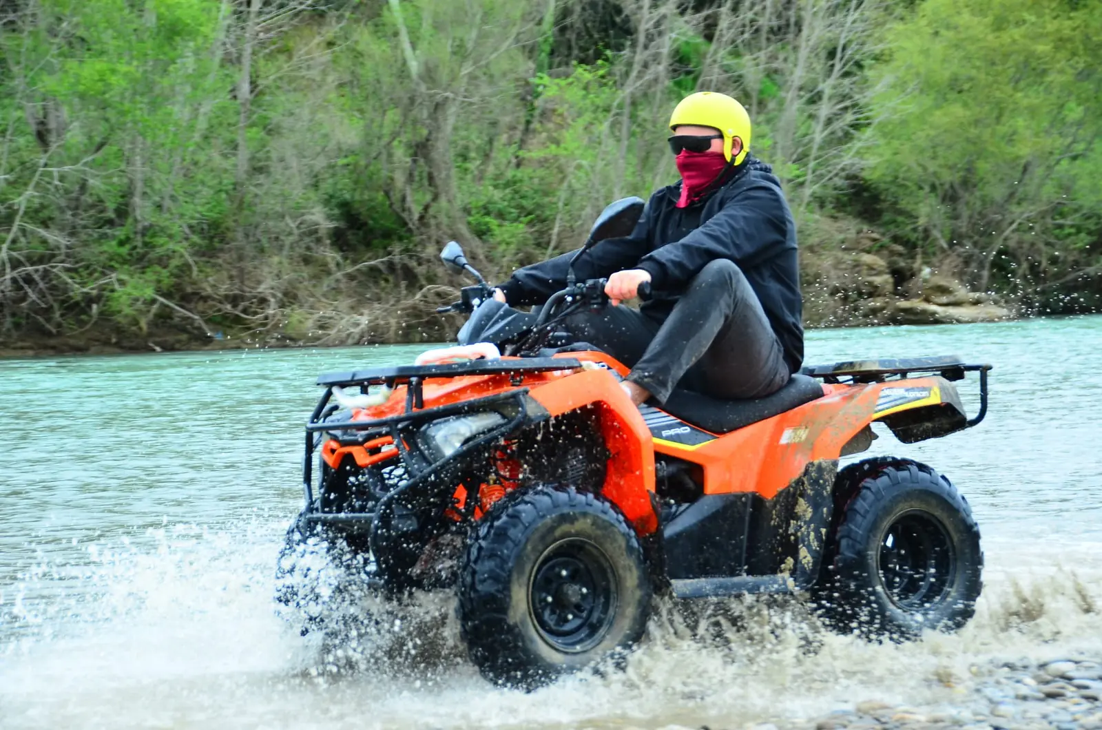 Quad safari rider crossing a shallow river on the off-road route behind Belek