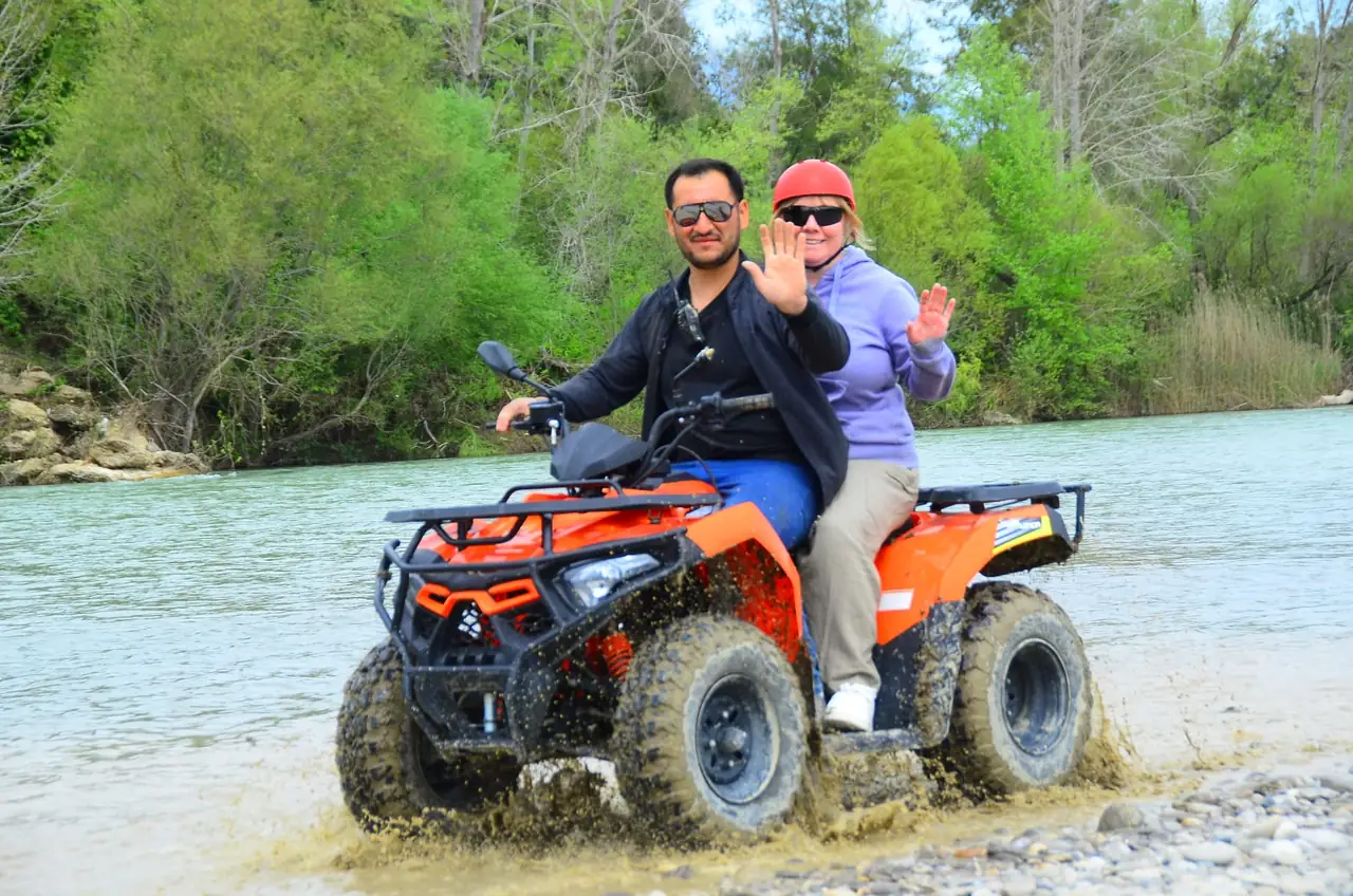 Two riders sharing one quad through a river crossing on the Belek quad safari