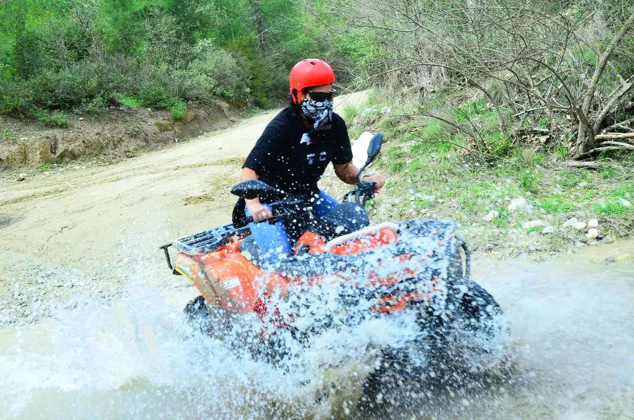 Quad throwing up spray through a shallow water section on the Belek safari route