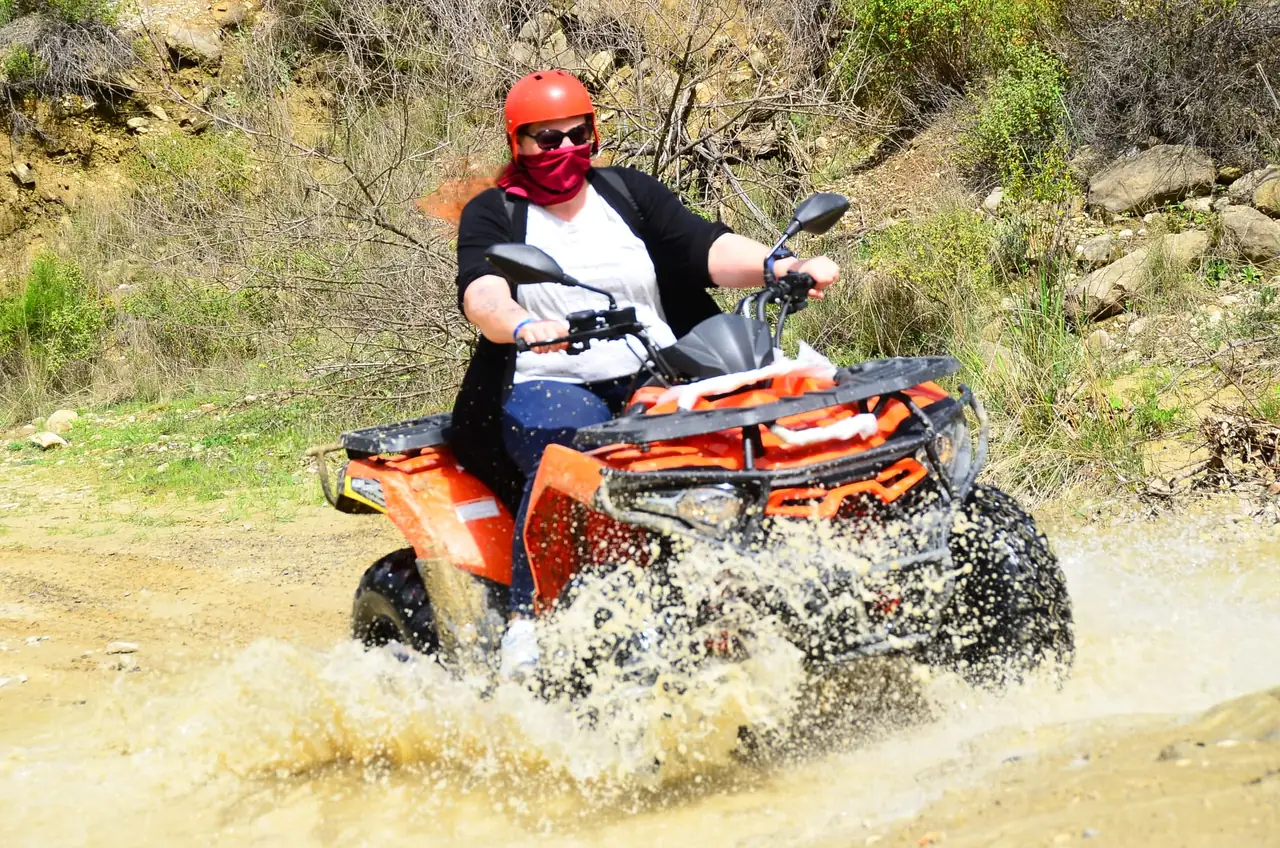 Rider steering a quad through a muddy stretch of the Belek backcountry trail