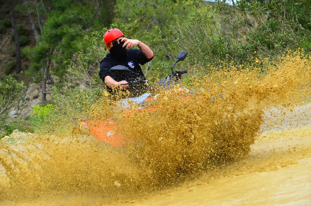 Quad rider kicking up mud on the dusty off-road track by the Köprüçay