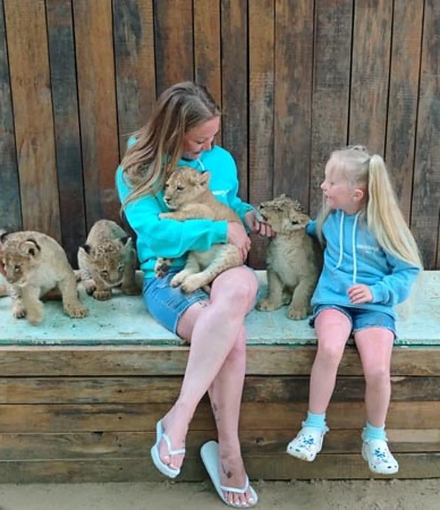 A mother and daughter with lion cubs at the zoo stop