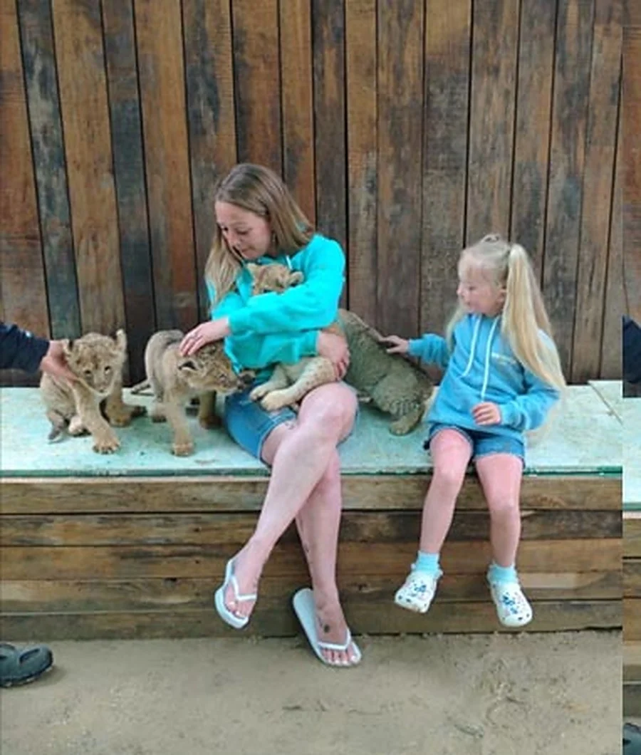 Children sitting with lion cubs at the zoo stop