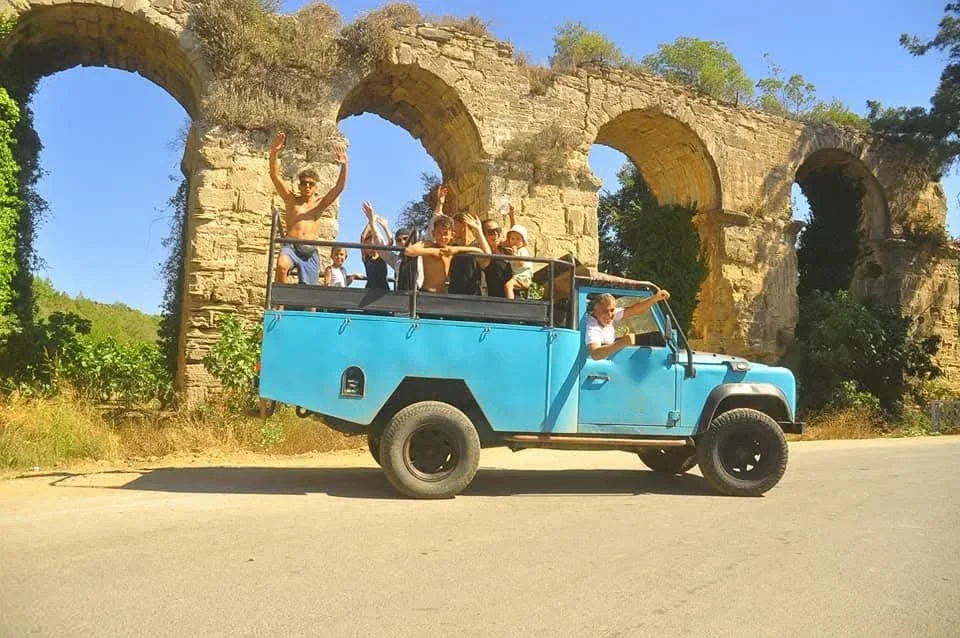 Open-top jeep beneath the Roman aqueduct arches